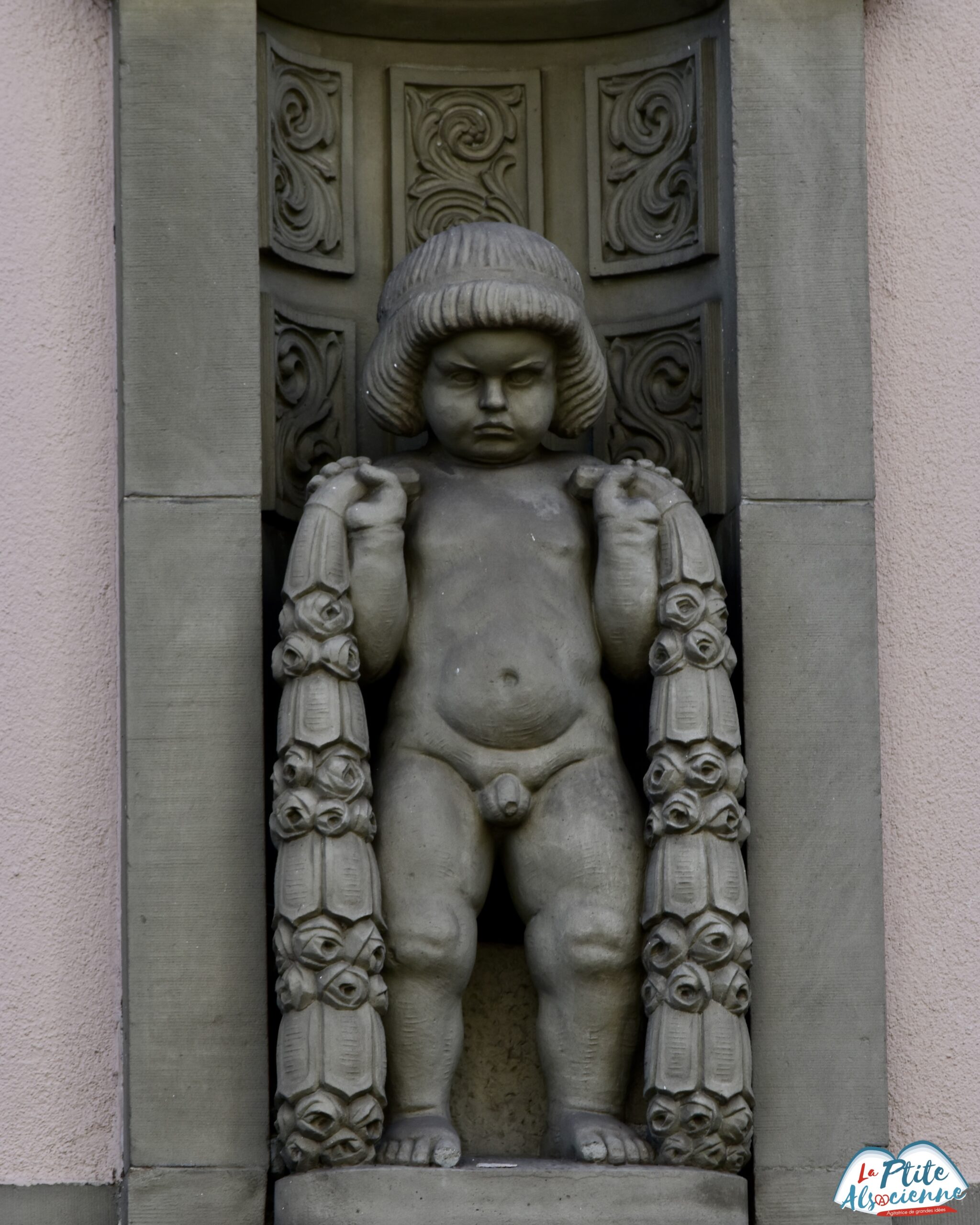 Schnockeloch Strasbourg – statue du petit garçon boudeur rue du 22 Novembre à Strasbourg. Sculpture en pierre du XIXe siècle sur la Maison Schimpf.